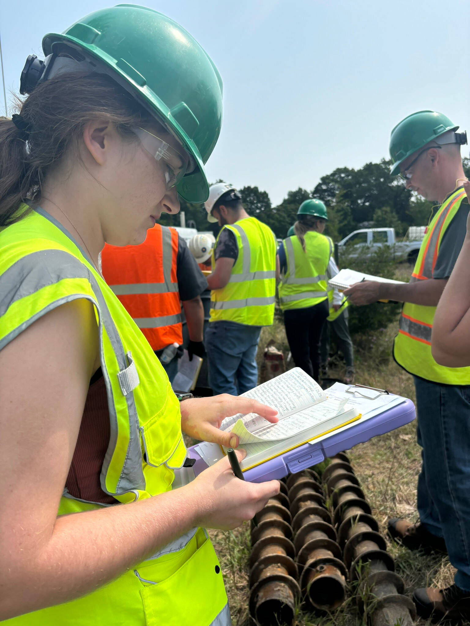 person wearing hard hat looking at notebook